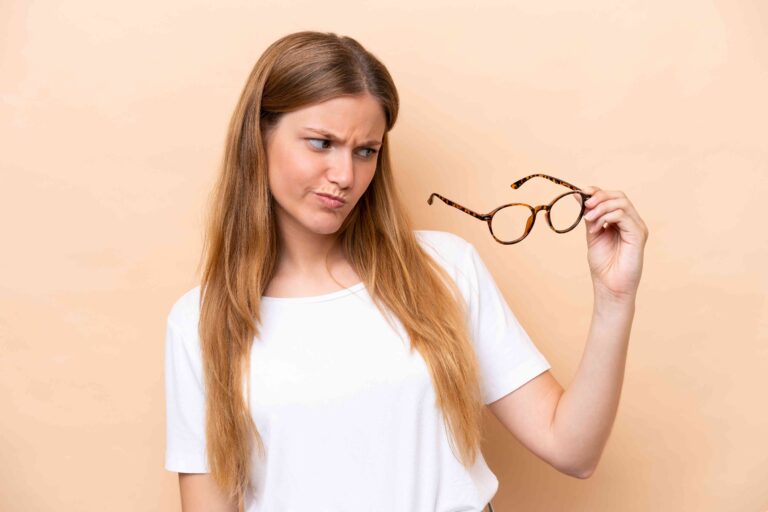 נערה עם קרטוקונוס אוחזת במשקפיים במבט לא מרוצה